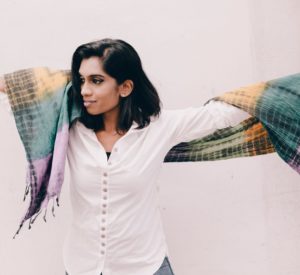 woman stretches arm with multi-colored scarf on shoulders