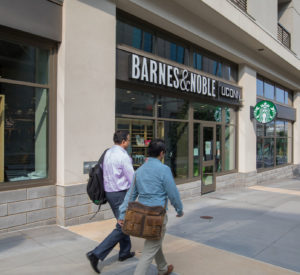 two men with bags walk in front of Barnes and Noble